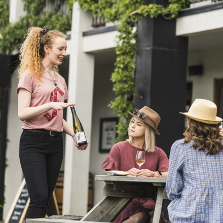 Four people on a wine tour enjoy being taken through a guided wine tasting at a winery cellar door in Marlborough, at the top of New Zealand's South Island