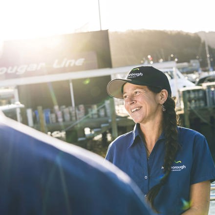 Smiling staff member in blue uniform on a boat in Picton Marina, in the Marlborough Sounds at the top of New Zealand's South Island