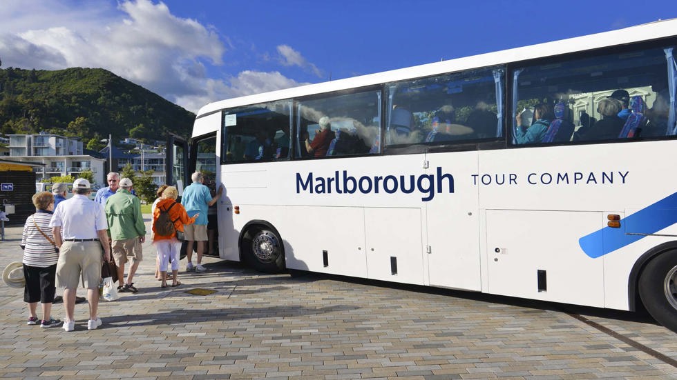 Coach with line of passenger boarding for a group tour, at Picton Marina in Marlborough at the top of New Zealand's South Island.