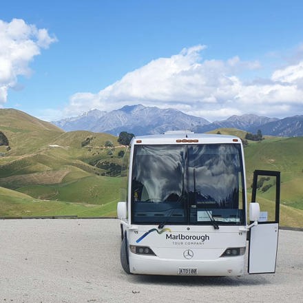 Large bus parked next to rolling hills in the country, near Blenheim in Marlborough at the top of New Zealand's South Island.