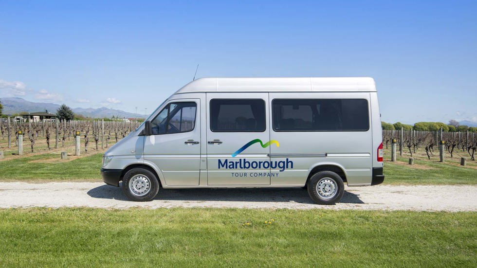 Silver van with Marlborough Tour Company logo on side parked in vineyard, near Blenheim in Marlborough at the top of New Zealand's South Island.