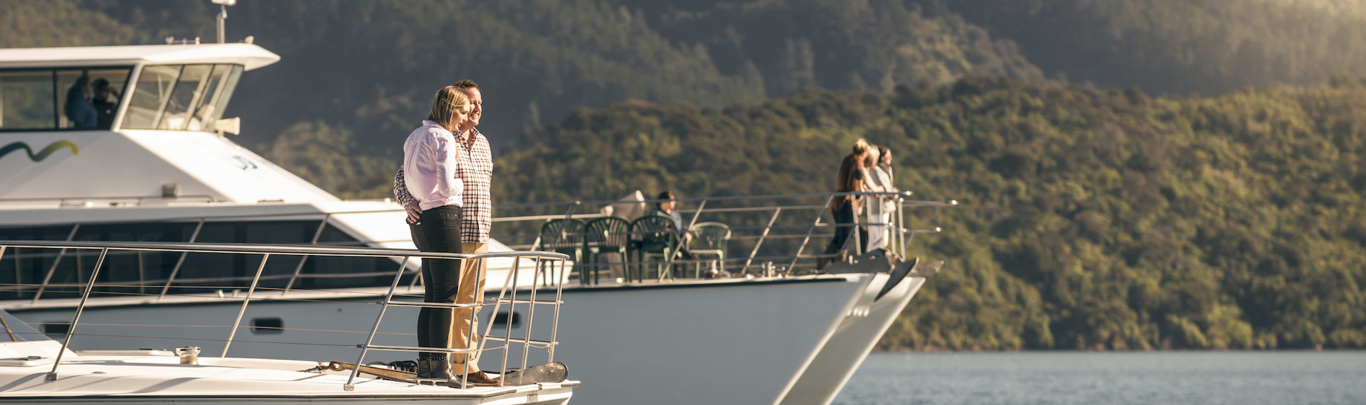 Two launches next to each other with passengers on the bow cruising in the Marlborough Sounds at the top of New Zealand's South Island.,  